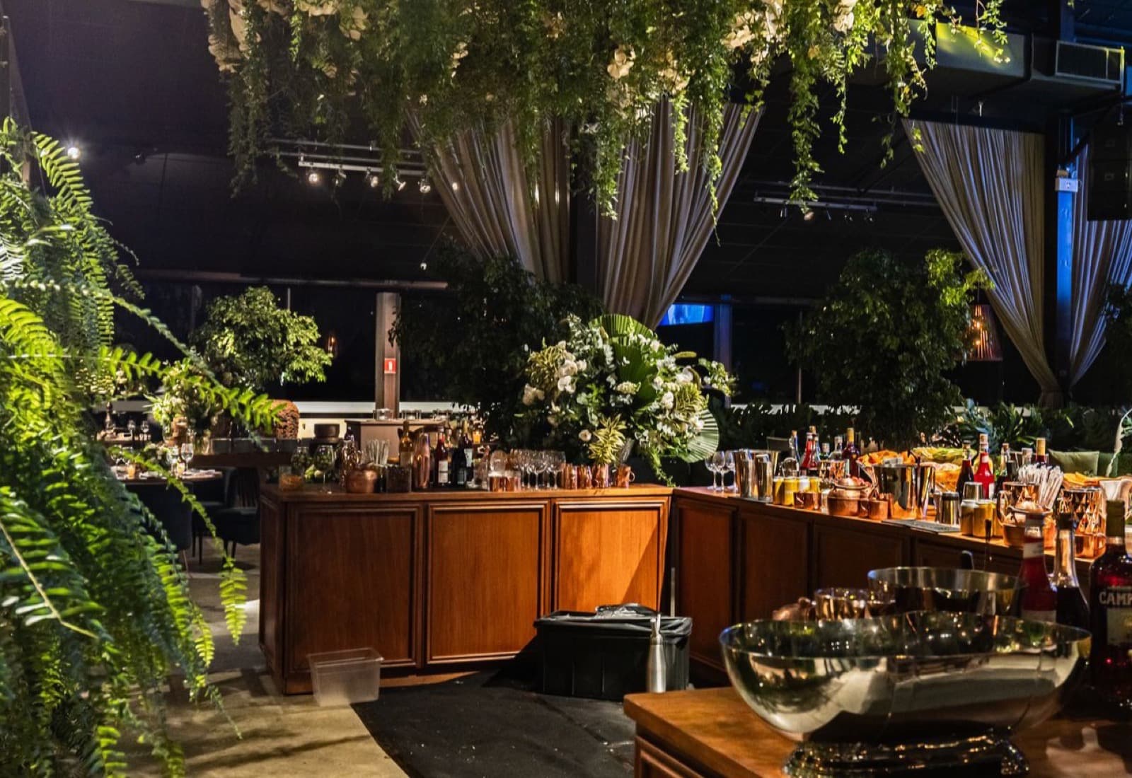 Ciel de feuillages retombants et de fleurs blanches suspendu au-dessus d'un bar en bois
